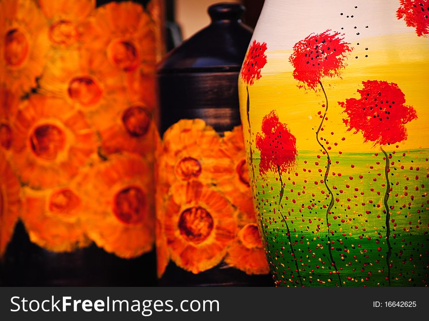 Handmade pottery detail with red flowers and green grass