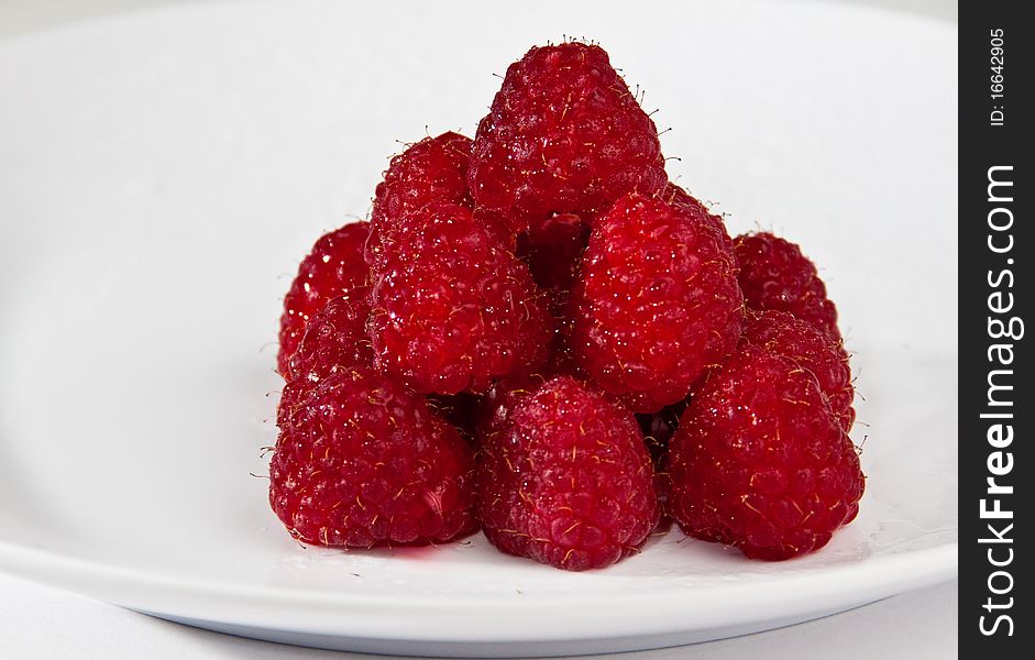 A pyramide of fresh raspberries on a white plate. A pyramide of fresh raspberries on a white plate