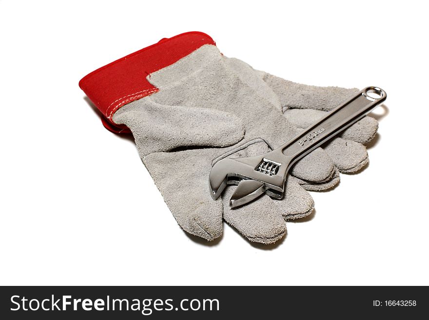 A pair of workmans gloves and a wrench. A pair of workmans gloves and a wrench