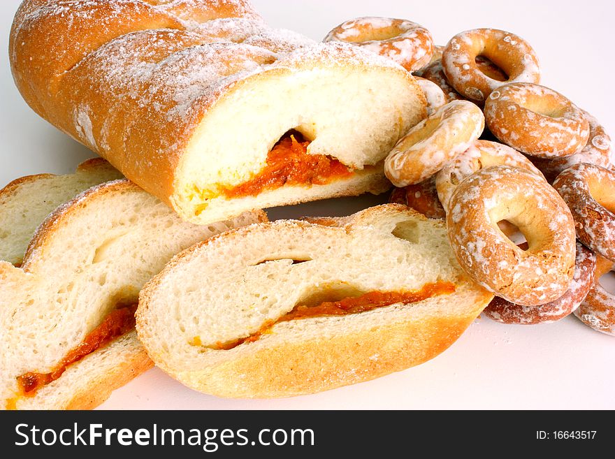 The rich ruddy roll is strewed by powdered sugar with a stuffing from dried apricots on a white background. The rich ruddy roll is strewed by powdered sugar with a stuffing from dried apricots on a white background