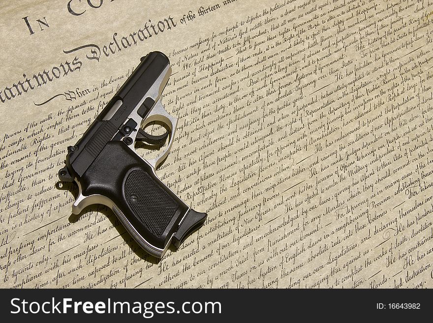 An automatic handgun rests on the Declaration of Independence. An automatic handgun rests on the Declaration of Independence.
