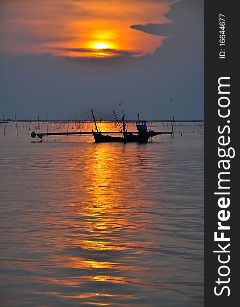 Silhouette of fishing boat in sunset over the sea