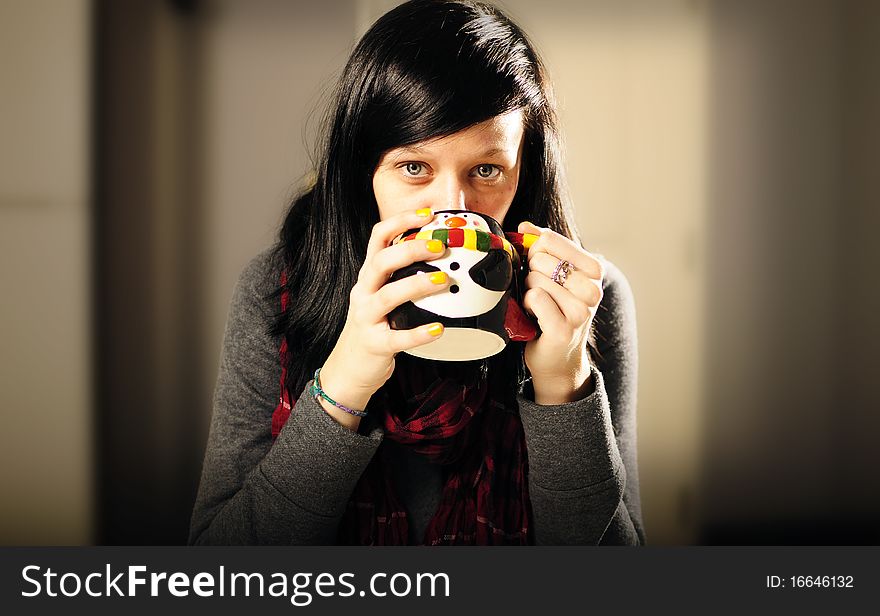 Girl staying warm drinking from a penguin cup. Girl staying warm drinking from a penguin cup