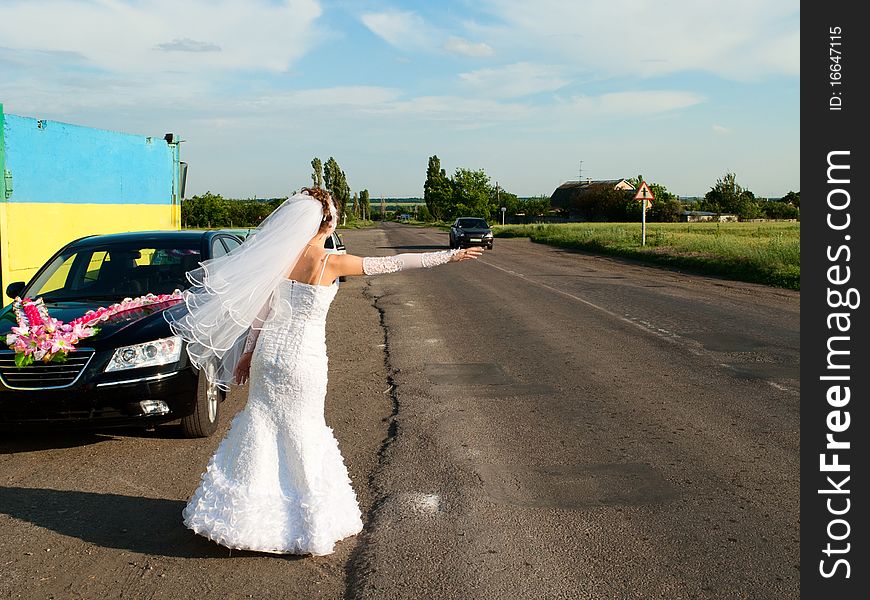 Young beautiful bride hitch-hike at the road