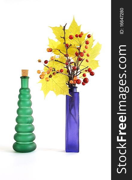 Autumn bouquet of branches with small apples and maple leaves to color a glass vase on a white background