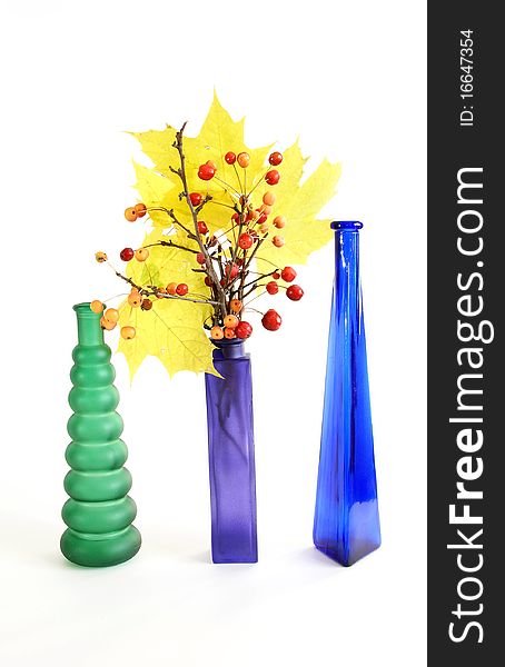Autumn bouquet of branches with small apples and maple leaves to color a glass vase on a white background