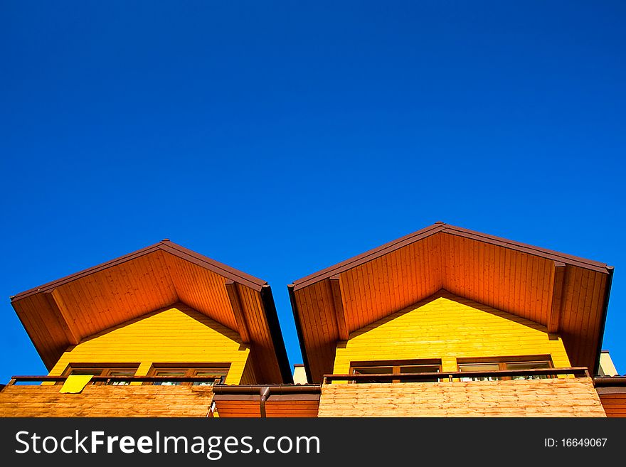 Part of yellow, wooden house under the clear, blue sky. Part of yellow, wooden house under the clear, blue sky.