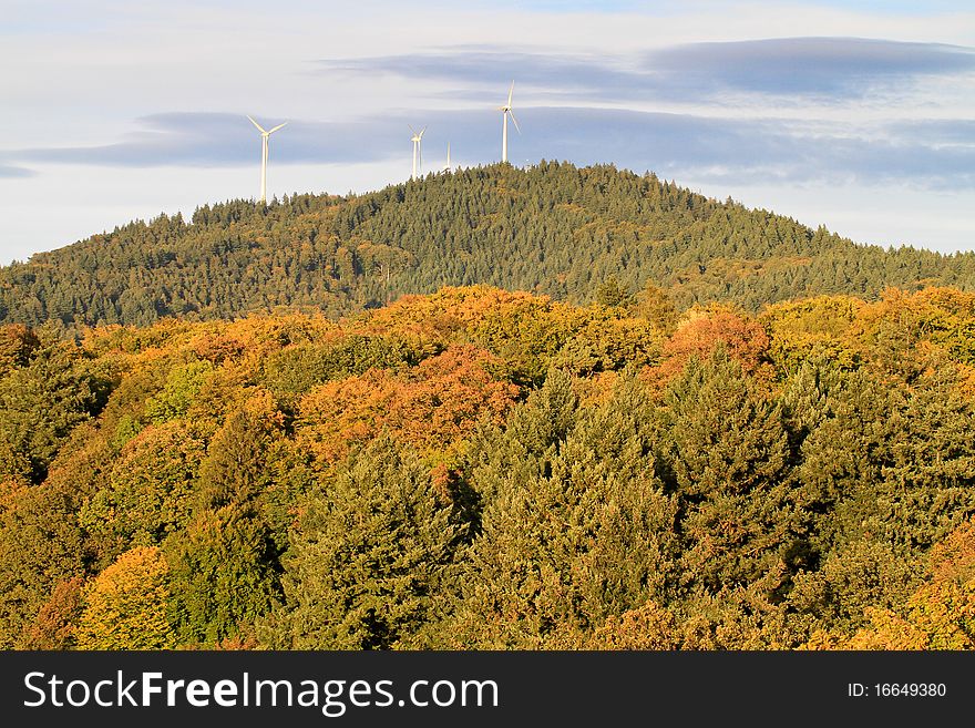 Wind energy mills over forest in fall