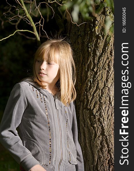 Young girl smiling and leaning on a tree. Young girl smiling and leaning on a tree