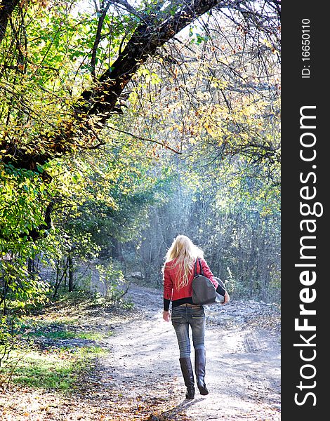 Young woman going away by forest road. Young woman going away by forest road