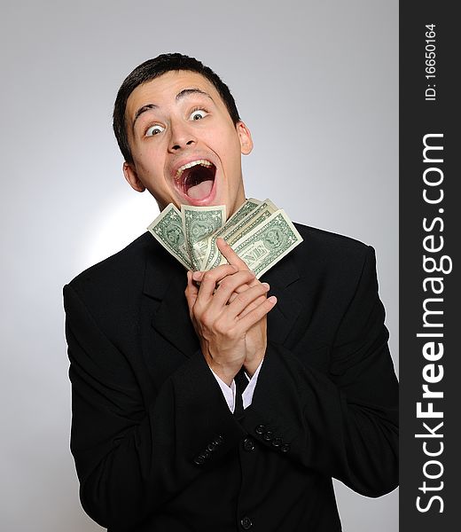 Expressions - Young handsome business man in black suit and tie counting money. gray background. Expressions - Young handsome business man in black suit and tie counting money. gray background