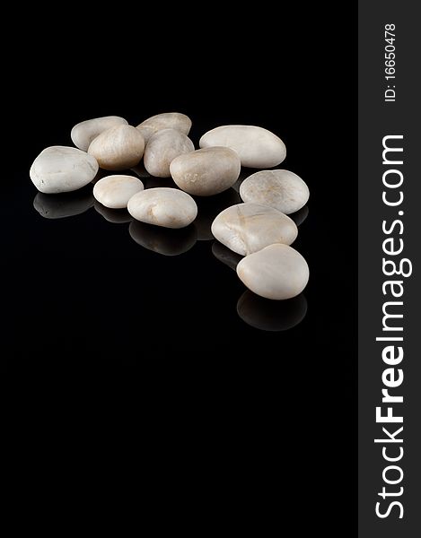 White stones on black background, mirror surface