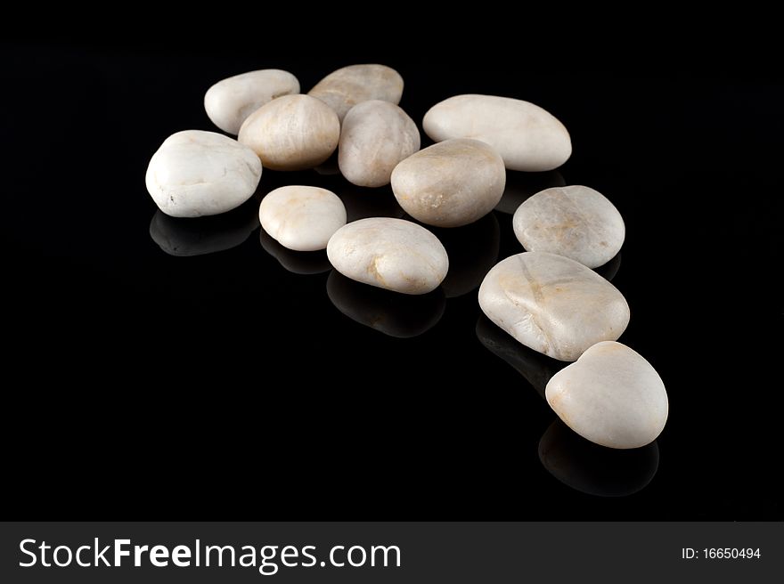 White stones on black background, mirror surface