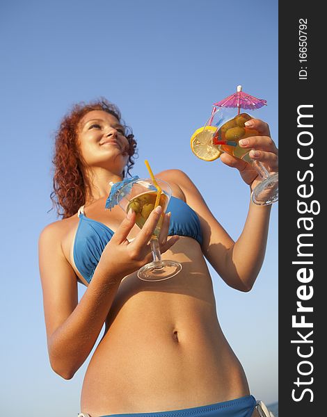 Young women with two martini glasses on the beachfront. Young women with two martini glasses on the beachfront