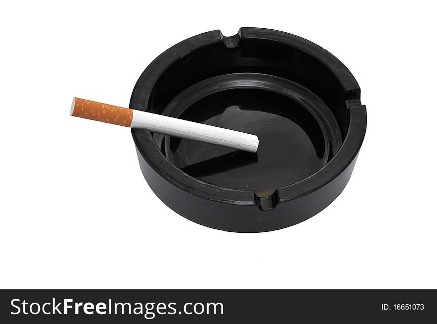 A black ashtray holds a cigarette. A black ashtray holds a cigarette