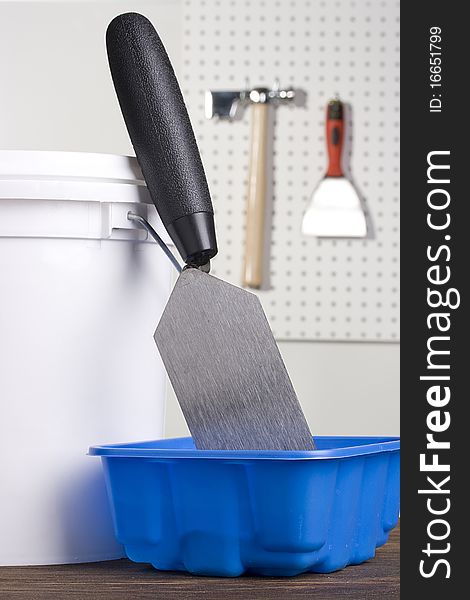 Plastering pallet in a blue plaster holder next to a white bucket.