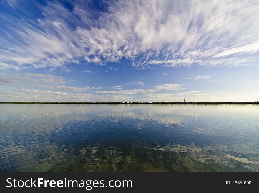 A wide angle shot of a calm lake under blue skies. A wide angle shot of a calm lake under blue skies.
