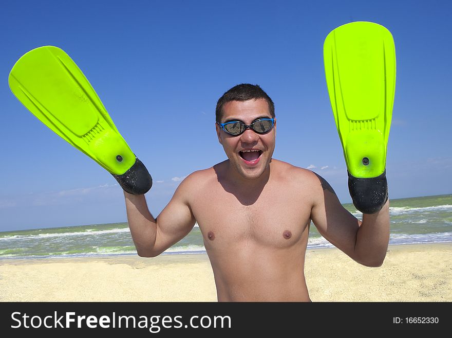 Portrait of smiling boy in swimming mask and fins on his hands against the sea and sky