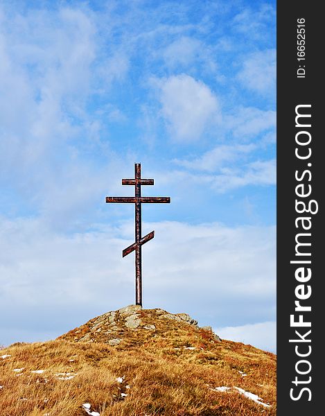 Cross against the sky on high hill made from metal