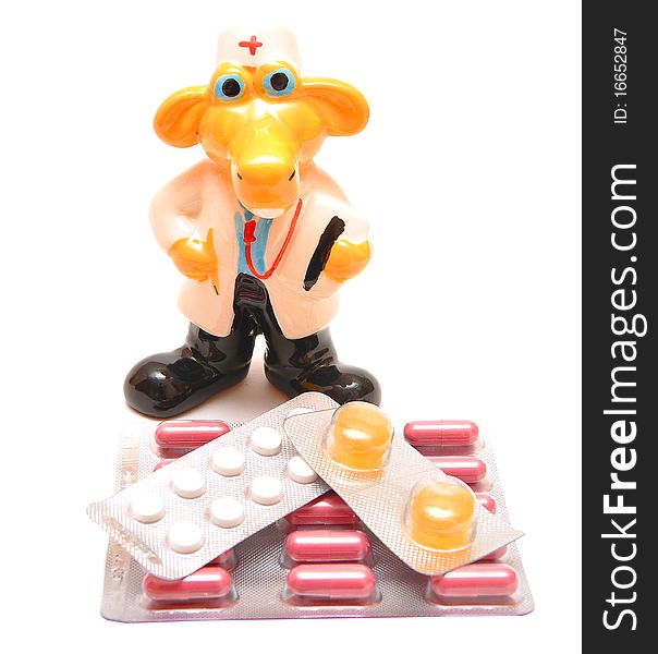 Toy in the form of doctor is sitting between pills