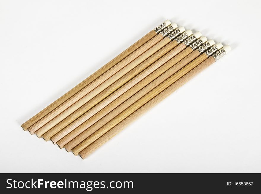 This image shows nine wooden pencils, perched on a clear surface and regrouped