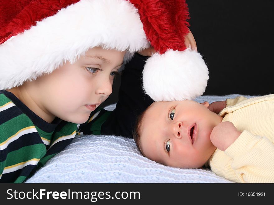 Boy wearing a christmas hat with his newborn brother. Boy wearing a christmas hat with his newborn brother