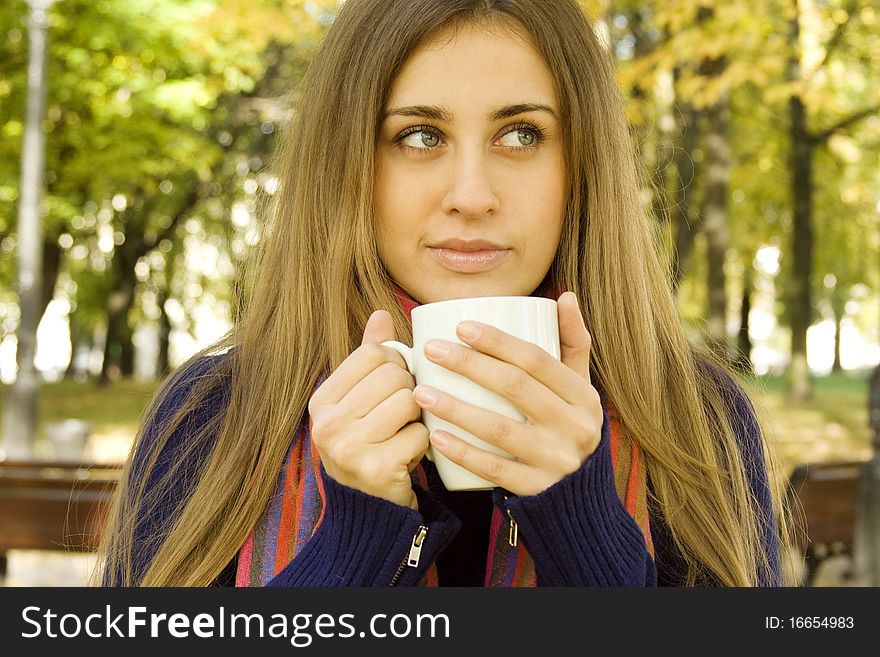 Autumn portrait of an attractive young woman wearing a soft sweater and scarf, holding a cup coffee (or tea). Autumn portrait of an attractive young woman wearing a soft sweater and scarf, holding a cup coffee (or tea)