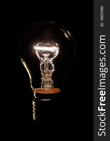 An illuminated light bulb on a black background. An illuminated light bulb on a black background