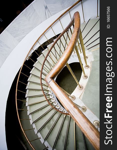 Bended brown wooden handhold of spiral stone stairs. Bended brown wooden handhold of spiral stone stairs