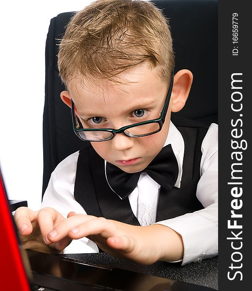 Child in white shirt and bow tie looks in laptop. Child in white shirt and bow tie looks in laptop