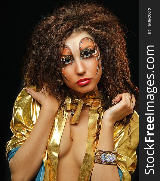 Young beauty girl with art make up in gold mant on black. Young beauty girl with art make up in gold mant on black