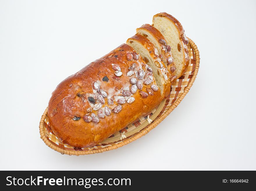 Loaf with raisins and nuts lying in a basket, a basket standing on a white background. Loaf with raisins and nuts lying in a basket, a basket standing on a white background.