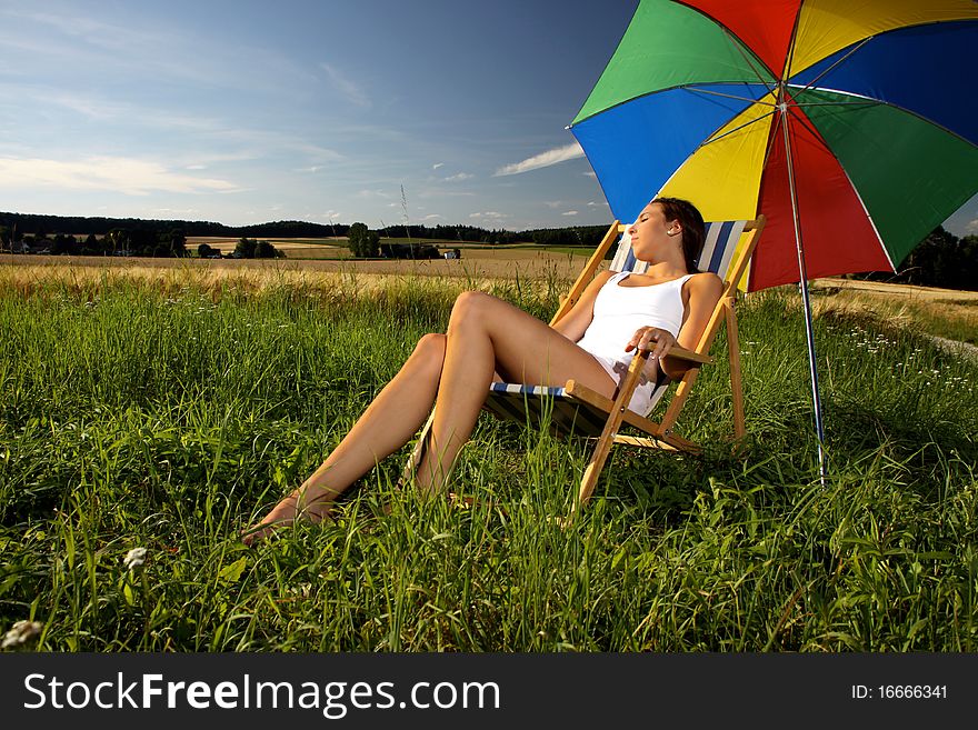 Young brunette girl sitting in a sun-chair. Young brunette girl sitting in a sun-chair