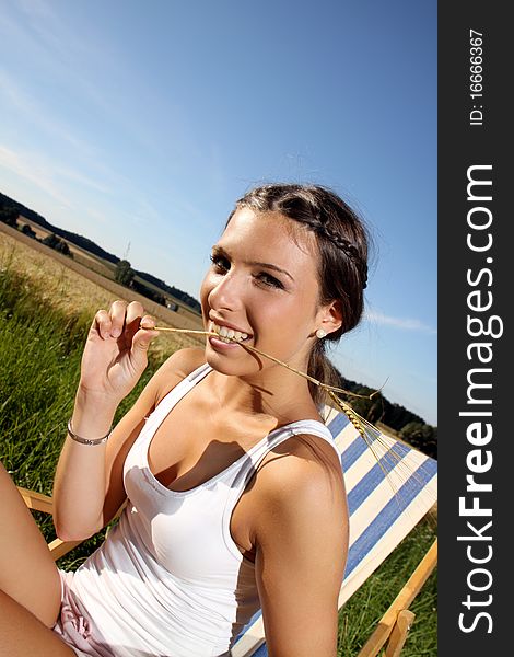 Young brunette girl sitting in a sun-chair. Young brunette girl sitting in a sun-chair