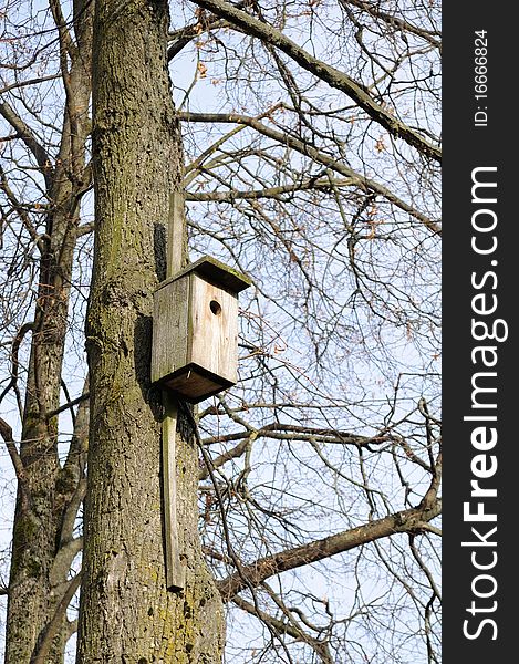 An empty wooden birdhouse on a tree in late autumn. An empty wooden birdhouse on a tree in late autumn