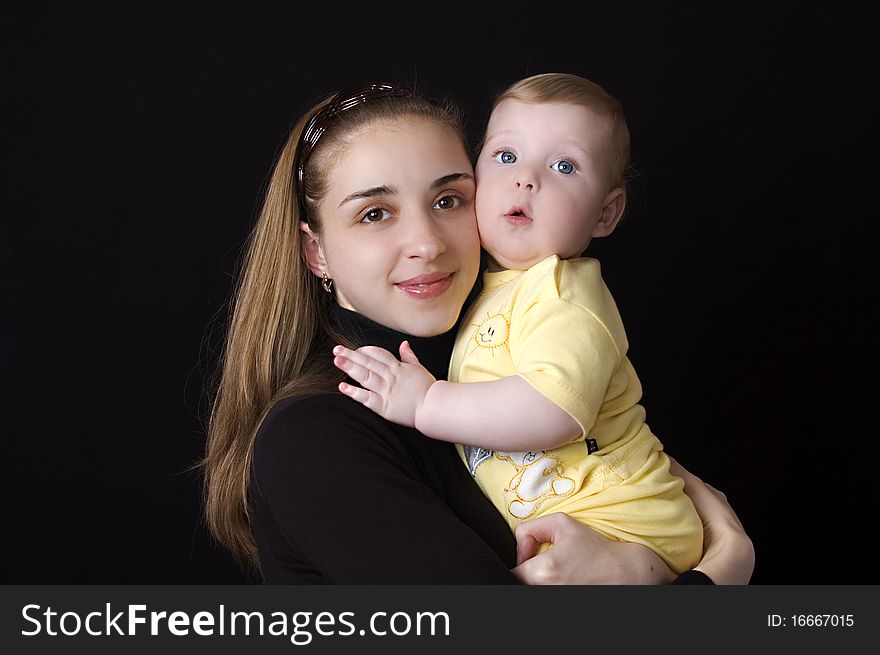 Beautiful baby and mother on a black background. Beautiful baby and mother on a black background