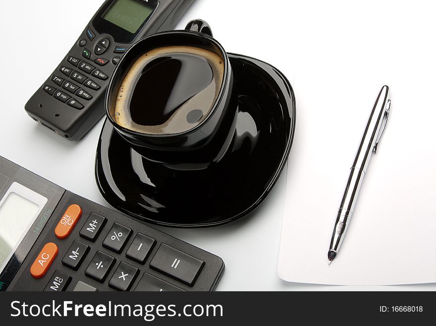 Coffee mug, calculator, pens, phone on white table