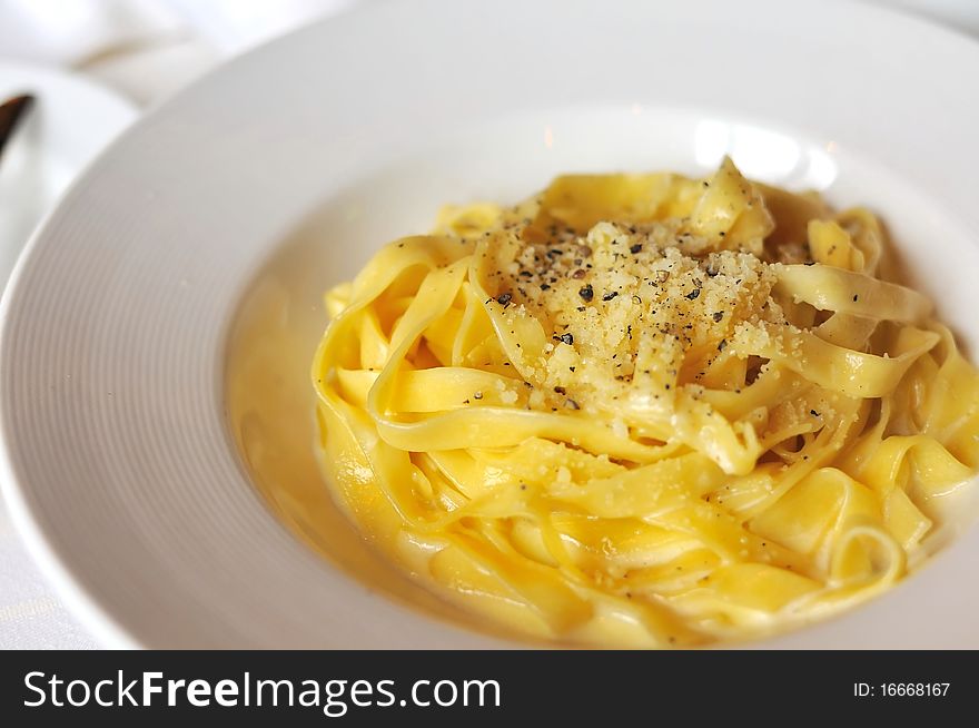 Closeup of tasty pasta cooked in cream sauce and served with shredded cheese.