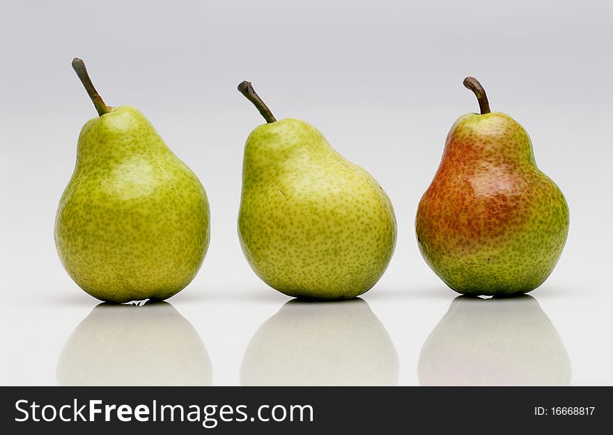 Three ripe pears resting on a white board