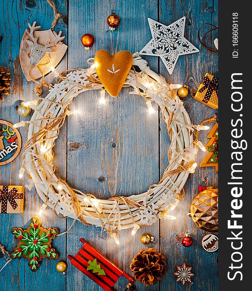 New year decorations around Christmas wreath burning lights garlands on blue wooden background. View from above. Flat lay. copy space. New year decorations around Christmas wreath burning lights garlands on blue wooden background. View from above. Flat lay. copy space