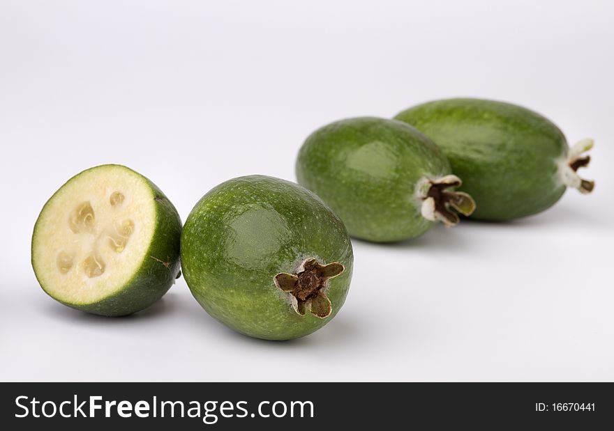 Close-up image of feijoa fruits, three whole and one cut in half. Close-up image of feijoa fruits, three whole and one cut in half.