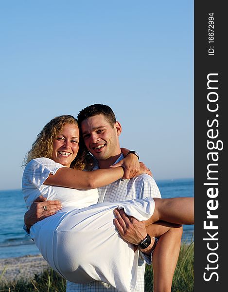 A happy woman and man in love at beach. The the young man is lifting his girlfrind. A happy woman and man in love at beach. The the young man is lifting his girlfrind.