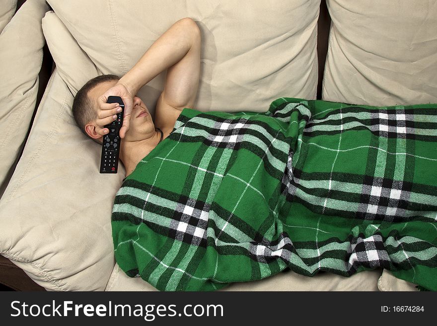 A young man sleeping on the couch with remote control. A young man sleeping on the couch with remote control