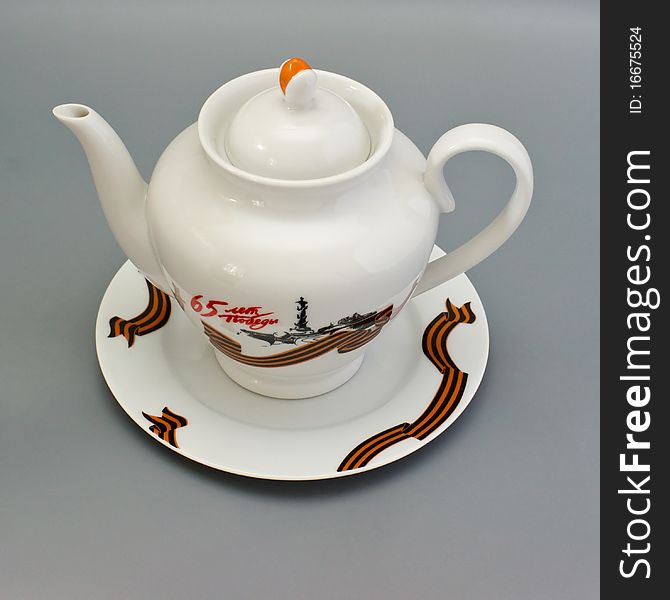 White porcelain teapot and saucer on a gray background. White porcelain teapot and saucer on a gray background.