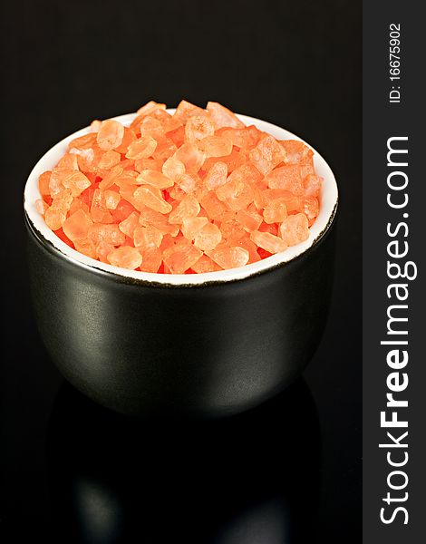 Orange bath salt black bowl on a black mirrored background. Orange bath salt black bowl on a black mirrored background.