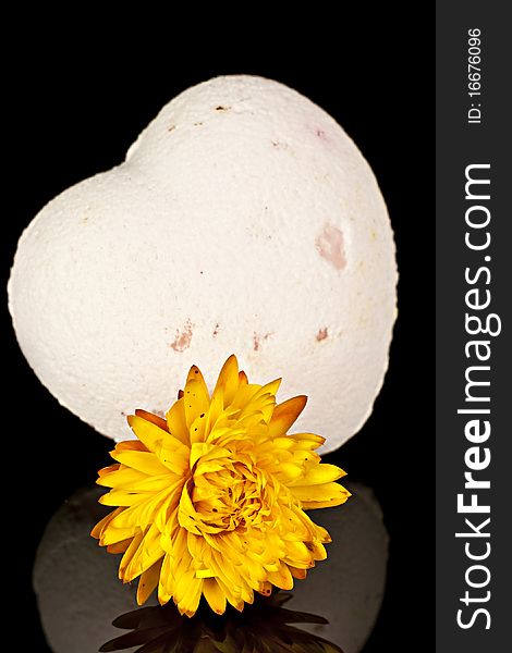 Bath salts in the form of the heart with a dry yellow flowers on a black background. Bath salts in the form of the heart with a dry yellow flowers on a black background.