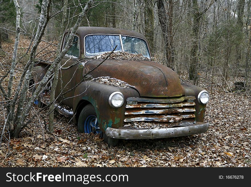 Just off the ebaten path an old pickup truck has been abandonded in the woods. Just off the ebaten path an old pickup truck has been abandonded in the woods