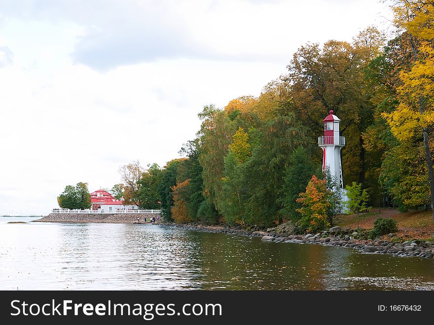 White and red lighthouse on bank of bay