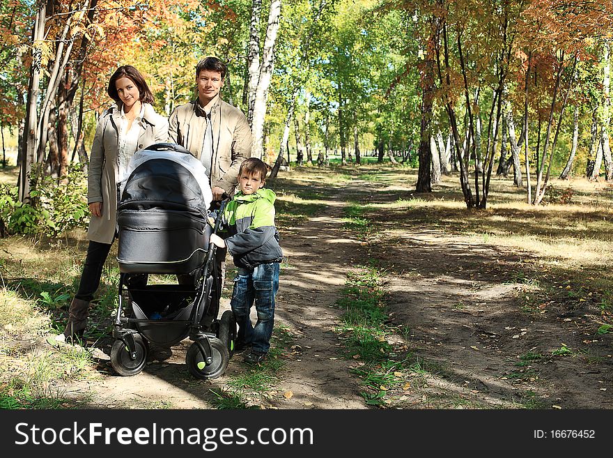 Happy family with two children walking at the autumn park.