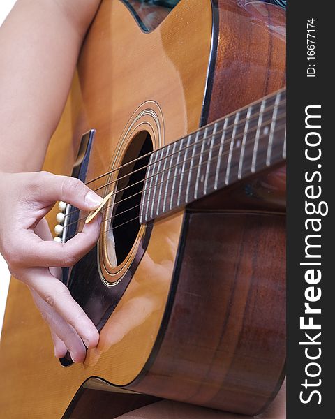 An Accoustic Guitar is played by a caucasian female hand.